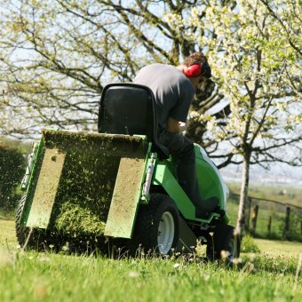 pépiniériste tond la pelouse avec une tondeuse verte